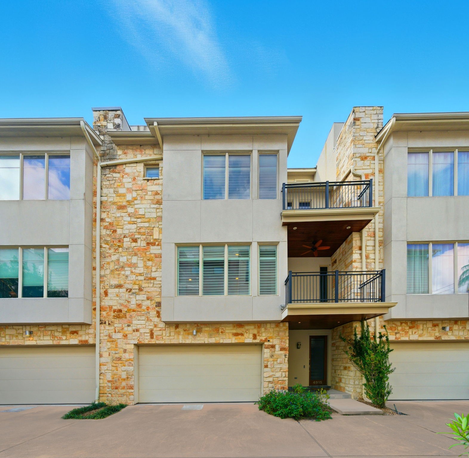 4915 Chenevert Street Houston, TX 77004 - Photo 6 of 41 Contemporary stone and stucco façade frames the welcoming entryway and spacious two-car garage, highlighting sleek architectural lines unique to this elevator-capable townhome. Private balconies and tall windows add sophistication and abundant natural light, all nestled in a gated community with low-maintenance landscaping.
