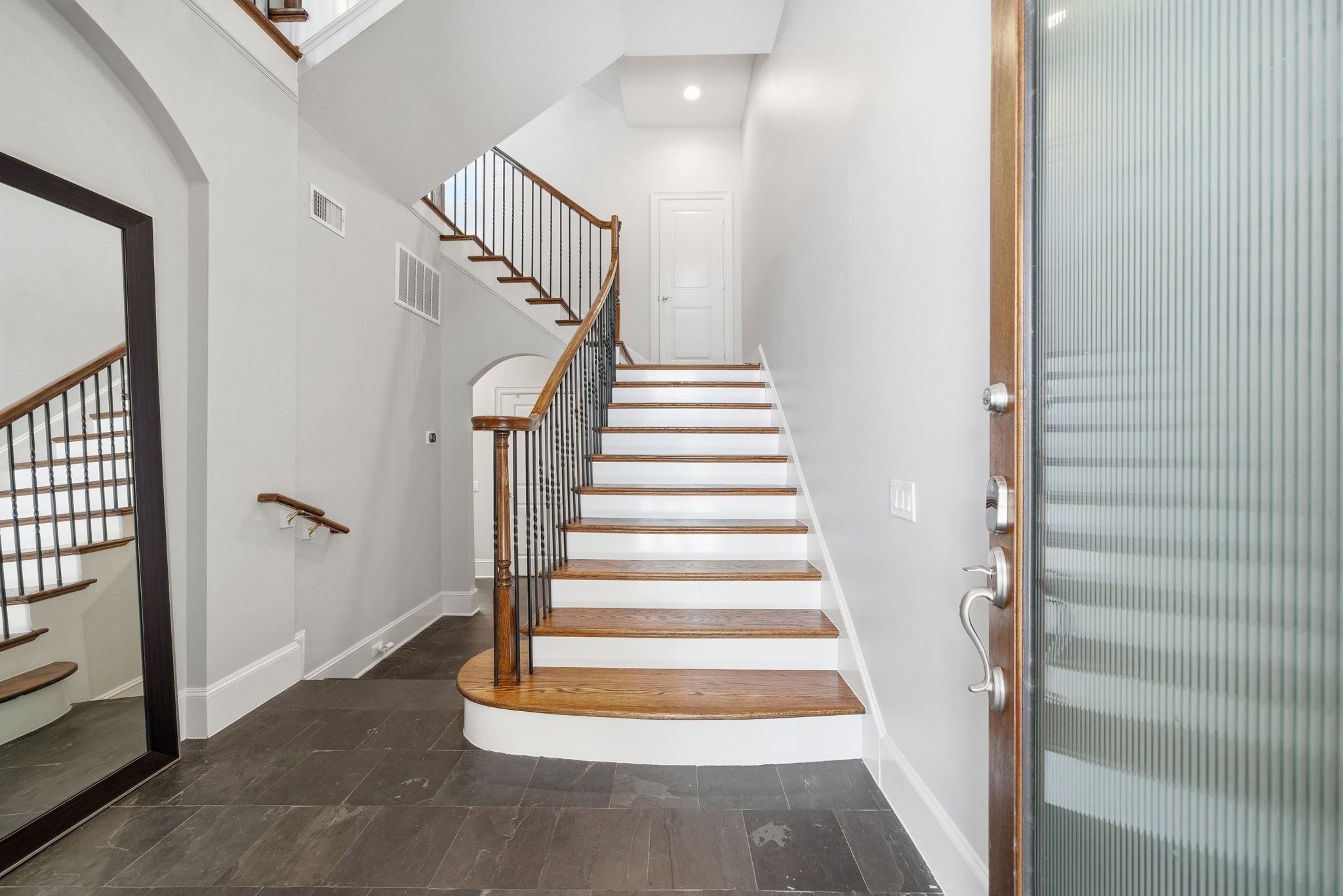 4915 Chenevert Street Houston, TX 77004 - Photo 8 of 41 Step inside to a contemporary foyer featuring sleek slate floors, a striking hardwood staircase with iron balusters, and towering ceilings. The entryway’s open layout and elevator-capable design create a sophisticated welcome, setting the tone for easy living in this exclusive gated community.