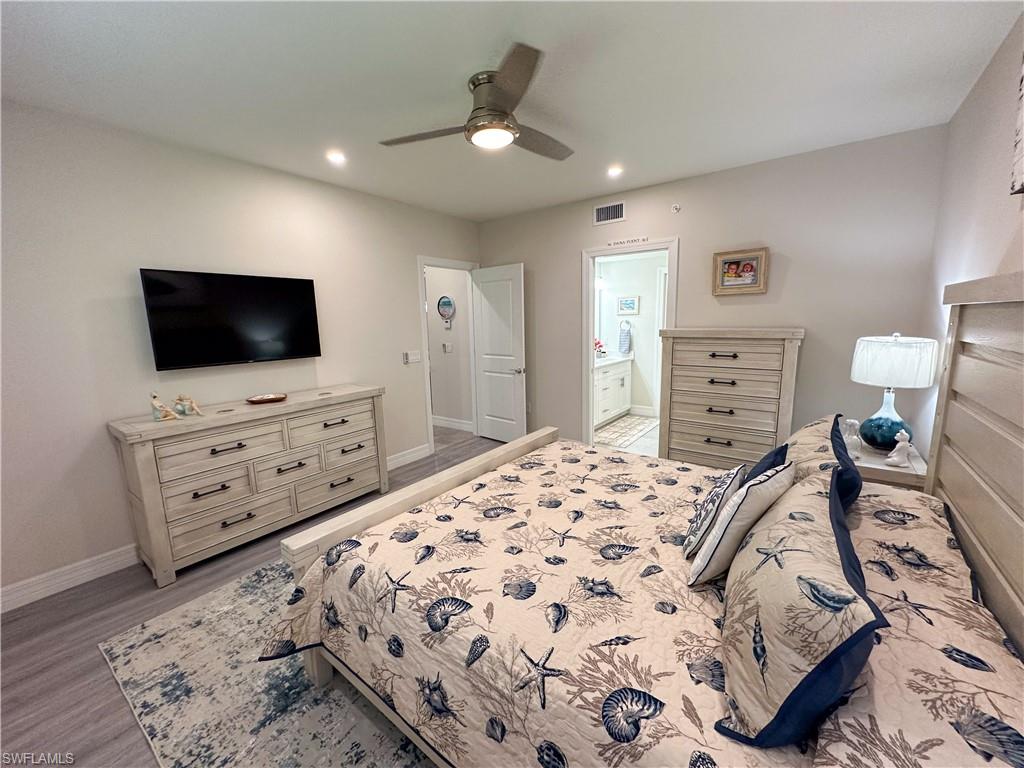 250 Indies Drive East, Unit 101 Naples, FL 34114 - Photo 14 of 49 a bedroom with a bed and flat screen tv