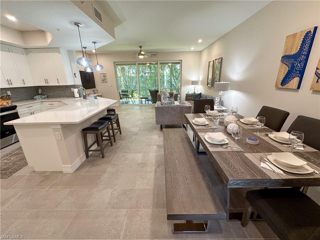 250 Indies Drive East, Unit 101 Naples, FL 34114 - Photo 34 of 49 a kitchen with a stove a refrigerator a sink dishwasher with a dining table and chairs