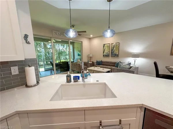 a view of a kitchen with kitchen island a large window cabinets a sink and a counter top space
