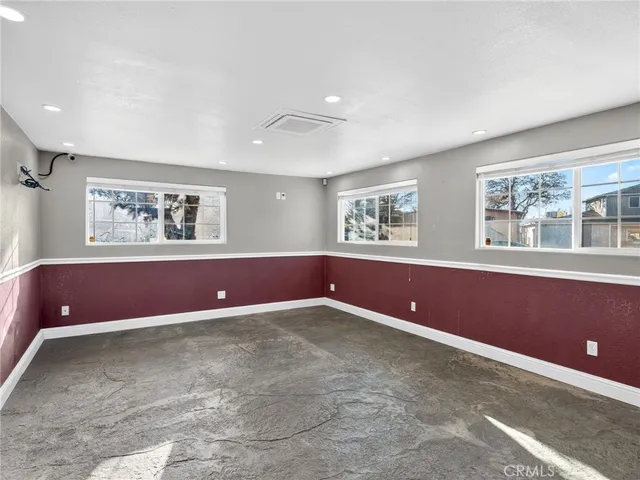a view of an empty room with a window and a kitchen