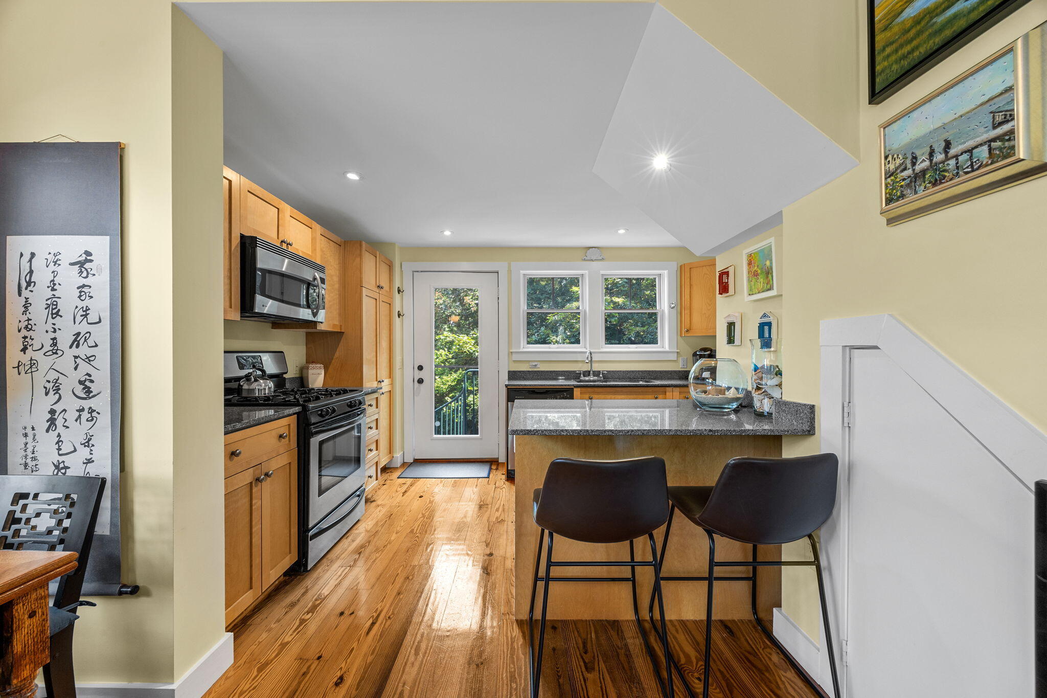 3 Meadow Road, Unit 2 Provincetown, MA 02657 - Photo 8 of 26 a kitchen with stainless steel appliances granite countertop a stove a refrigerator a kitchen island a dining table and chairs with wooden floor