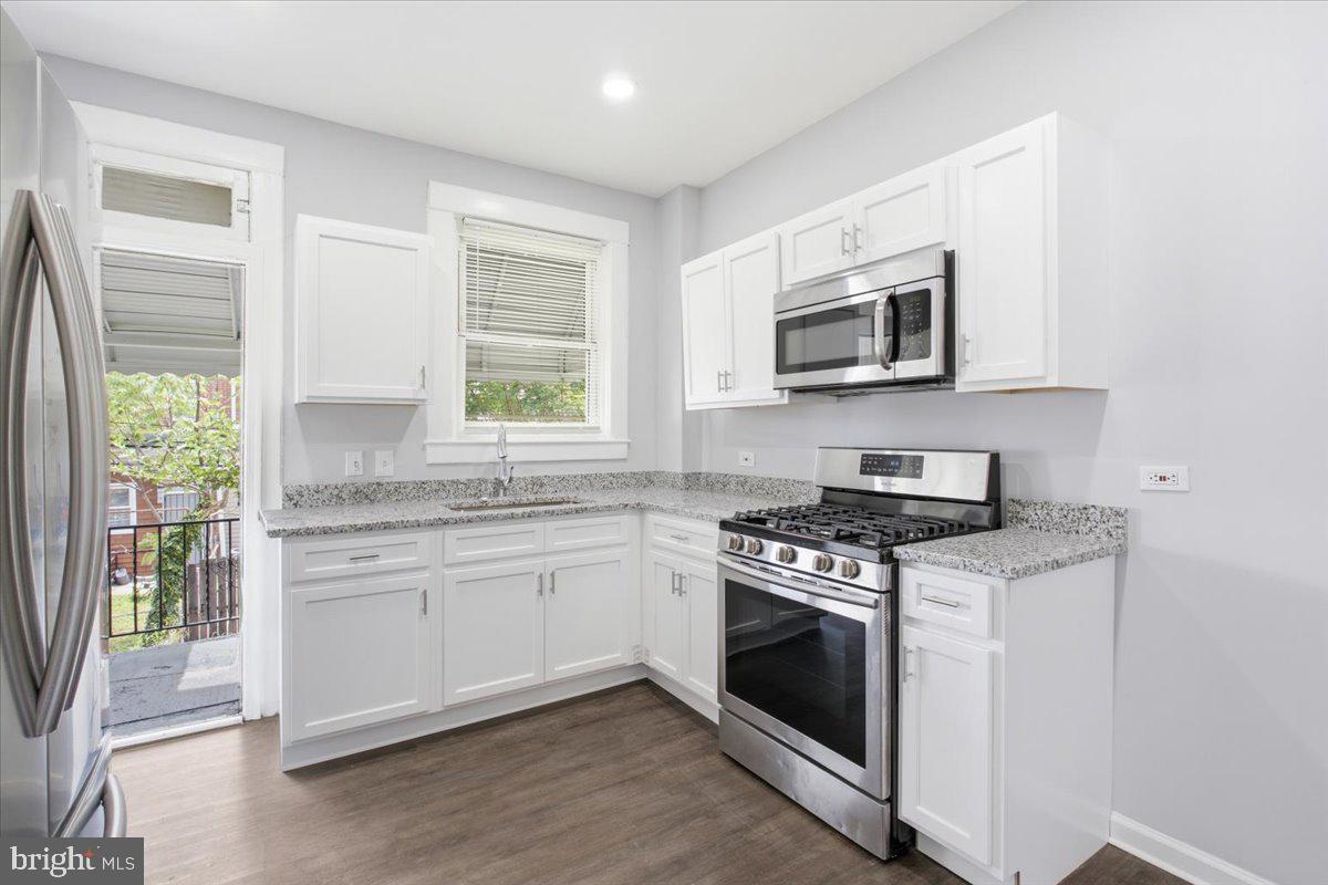 1231 North Potomac Street Baltimore, MD 21213 - Photo 9 of 25 a kitchen with stainless steel appliances granite countertop white cabinets a stove top oven and sink