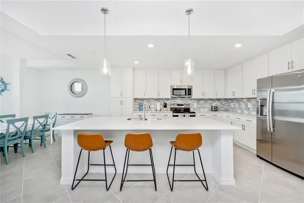 a large kitchen with stainless steel appliances kitchen island granite countertop a large stove a sink dishwasher and white cabinets with wooden floor