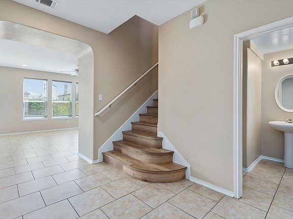 904 Lonesome Lilly Way Pflugerville, TX 78660 - Photo 16 of 34 Entryway featuring tiled flooring, a wooden staircase with a white handrail, and an arched doorway leading to a room with windows
