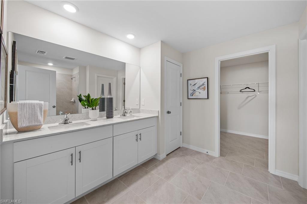 12265 Savanna Lakes Boulevard Lehigh Acres, FL 33936 - Photo 16 of 31 Full bathroom with tiled shower, double vanity, a walk in closet, tile patterned flooring, and recessed lighting