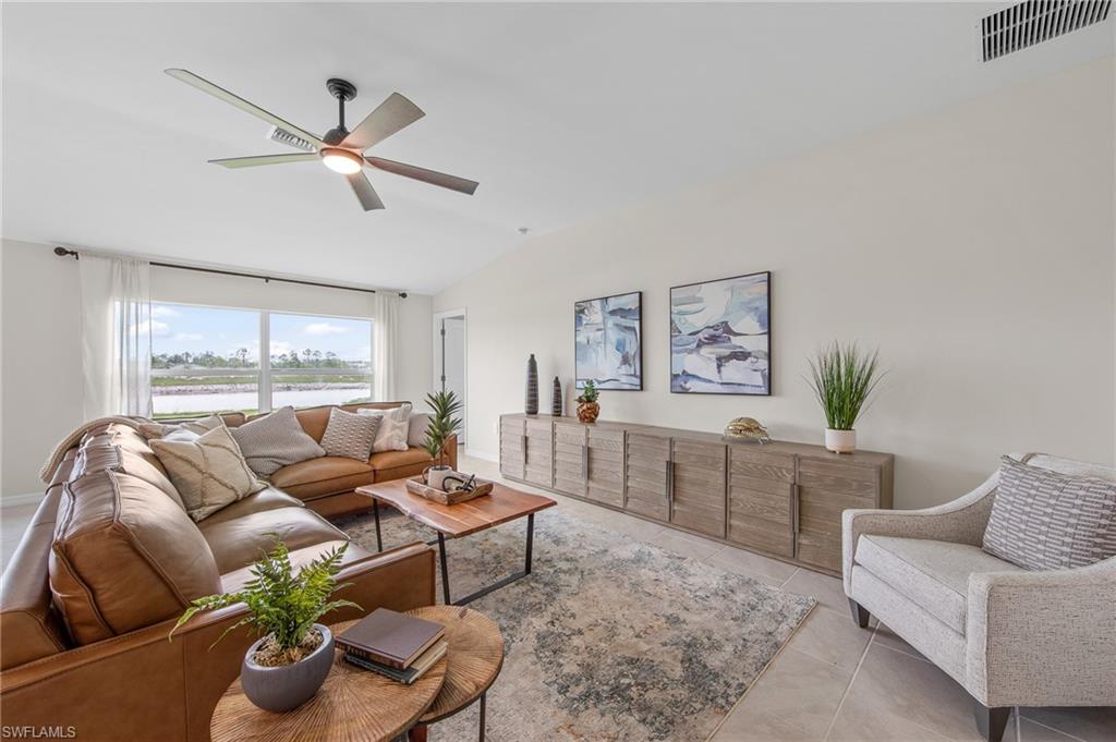12265 Savanna Lakes Boulevard Lehigh Acres, FL 33936 - Photo 6 of 31 Living room with a ceiling fan, vaulted ceiling, a water view, and light tile patterned flooring