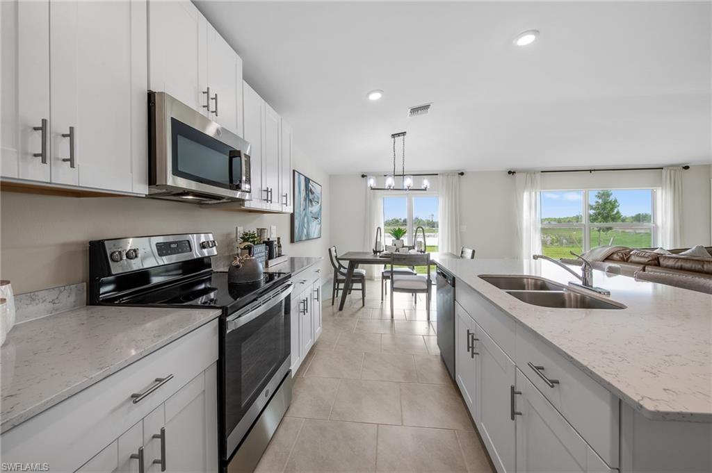 12265 Savanna Lakes Boulevard Lehigh Acres, FL 33936 - Photo 9 of 31 Kitchen featuring appliances with stainless steel finishes, a chandelier, white cabinets, recessed lighting, and light tile patterned floors