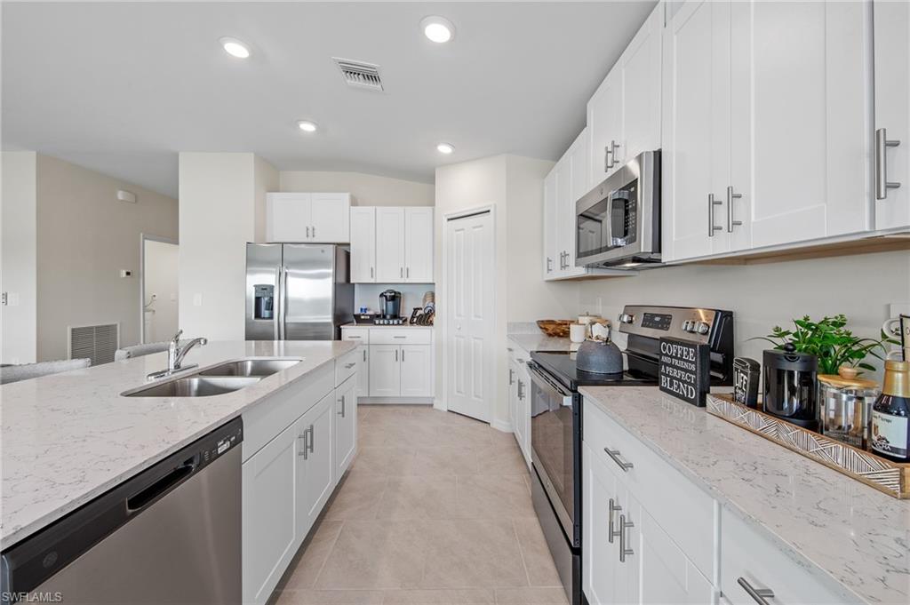 12265 Savanna Lakes Boulevard Lehigh Acres, FL 33936 - Photo 10 of 31 Kitchen featuring stainless steel appliances, light stone counters, white cabinetry, recessed lighting, and light tile patterned flooring
