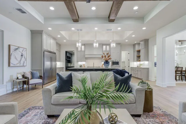 a living room with furniture kitchen view and a chandelier