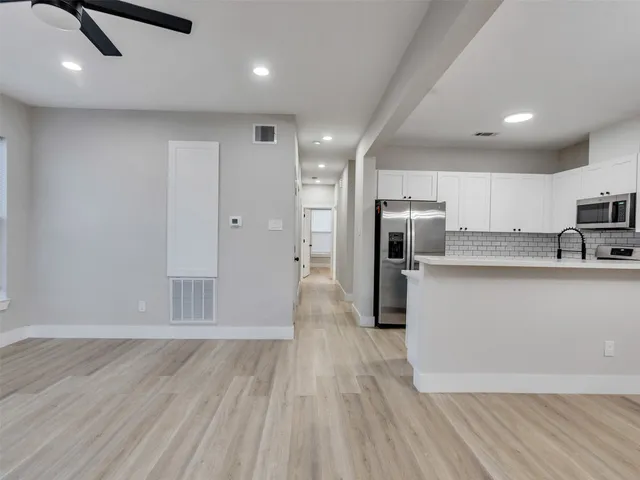 a large kitchen with stainless steel appliances granite countertop a large counter top a sink and a refrigerator