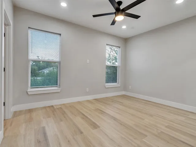 an empty room with windows and fan
