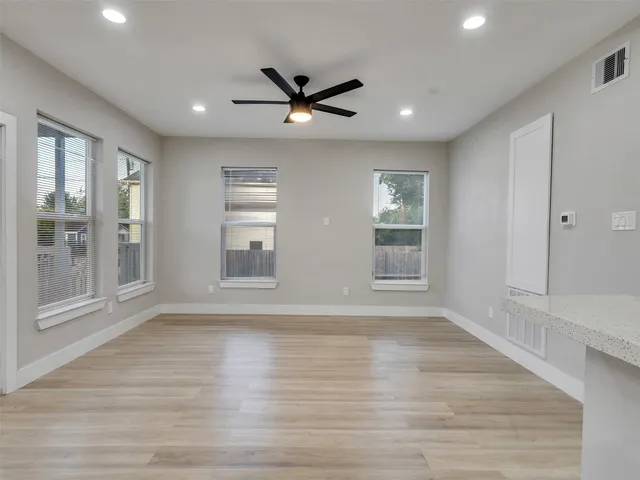 a view of an empty room with a window and wooden floor