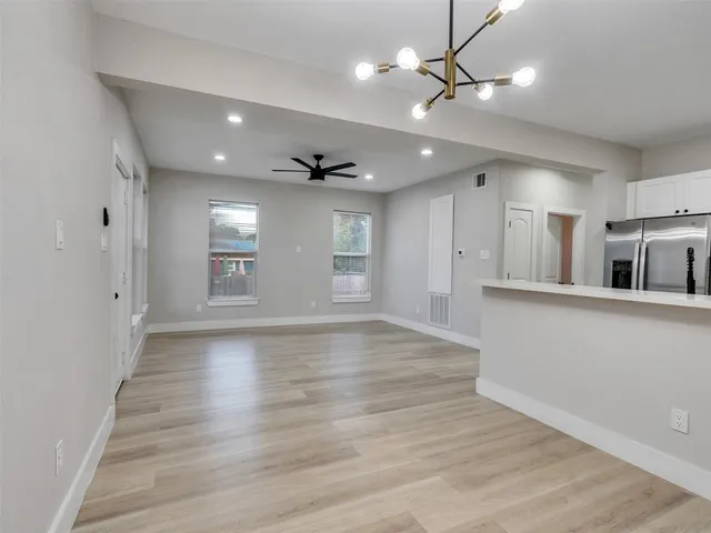 a view of an empty room with window and wooden floor