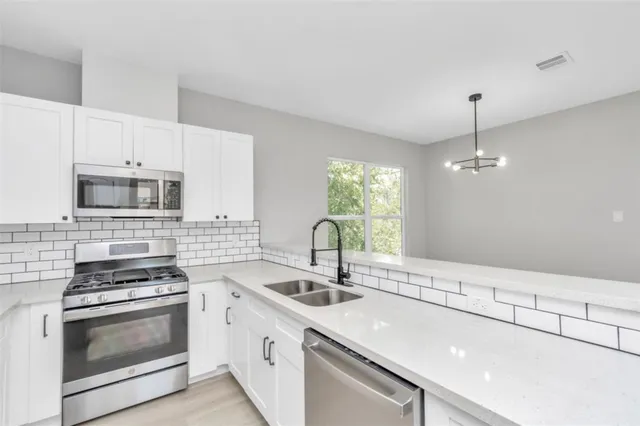 a kitchen with stainless steel appliances a sink stove and microwave