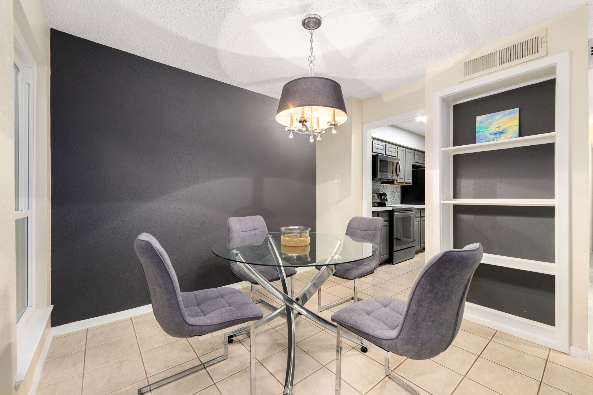 3200 South Gessner Road, Unit 228 Houston, TX 77063 - Photo 7 of 18 The stylish dining room features tile flooring, a dramatic dark accent wall, a elegant chandelier, built-in shelving, and a seamless pass-through view into the kitchen, a chic and functional space perfect for hosting!