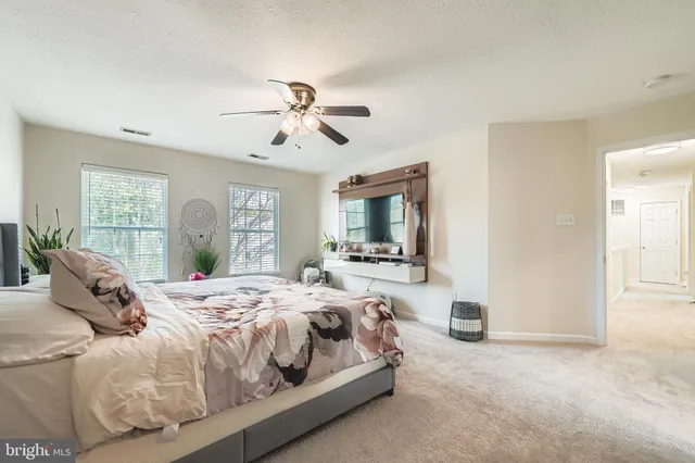 a bedroom with a large bed a flat tv screen and a dresser