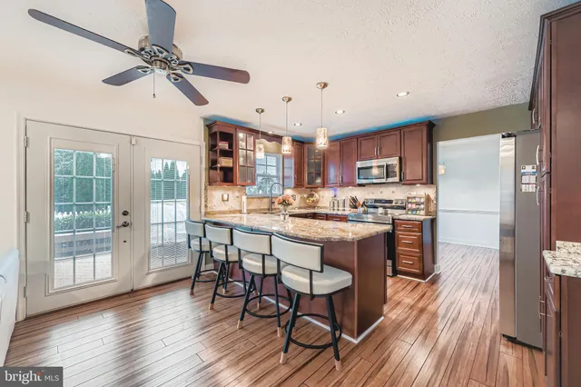 a kitchen with stainless steel appliances a dining table chairs refrigerator and cabinets