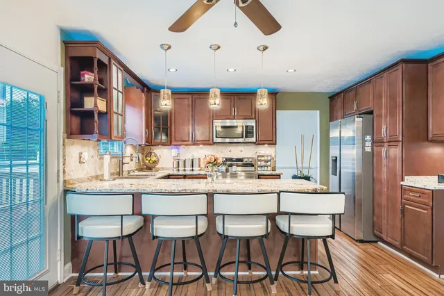 a kitchen with granite countertop a dining table chairs cabinets wooden floor and appliances