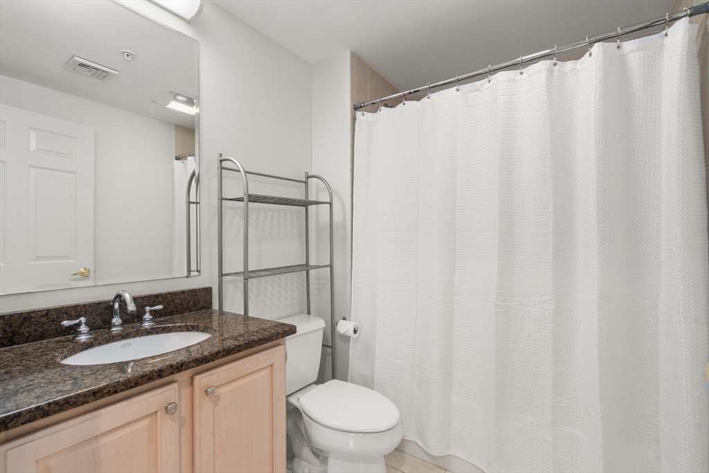 121 Centre Street, Unit PH3 Brookline, MA 02446 - Photo 27 of 32 a bathroom with a granite countertop sink and a mirror