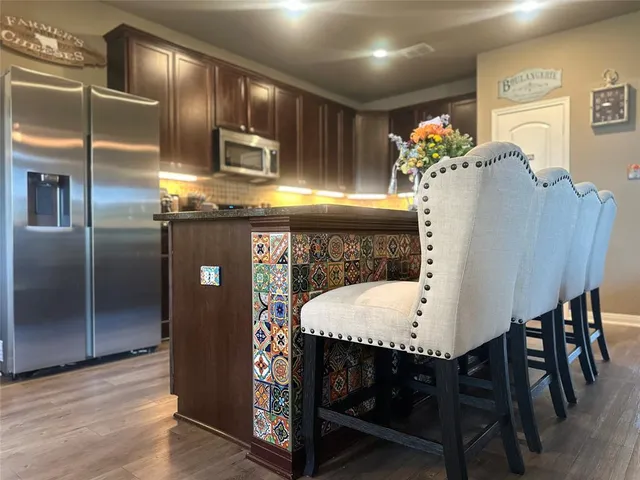 a kitchen with stainless steel appliances granite countertop a table chairs and granite counter tops