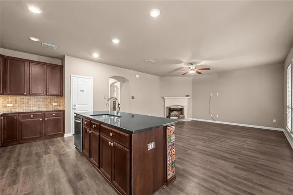 a kitchen with stainless steel appliances granite countertop a stove a sink dishwasher and a refrigerator with wooden floor