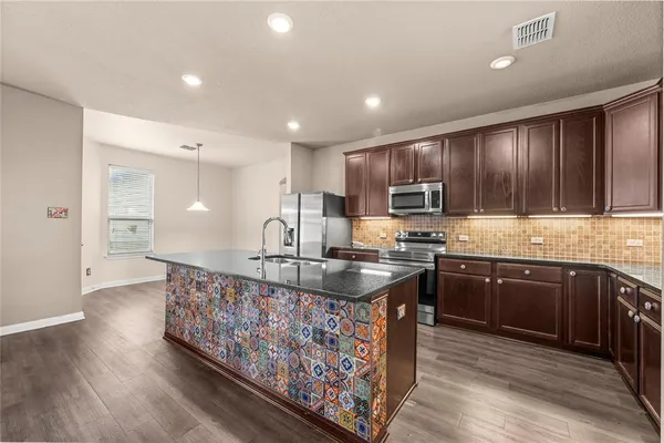 a kitchen with kitchen island granite countertop a sink stove and wooden cabinets