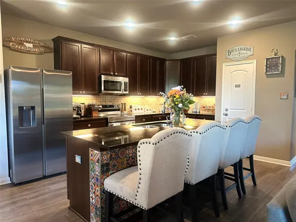 a kitchen with stainless steel appliances granite countertop a kitchen island a table and chairs