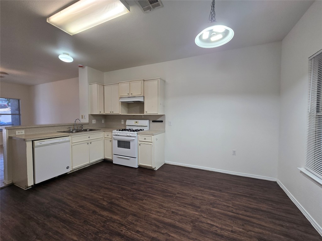 5404 Garden View Cove Austin, TX 78724 - Photo 8 of 28 a kitchen with white cabinets stainless steel appliances and wooden floor