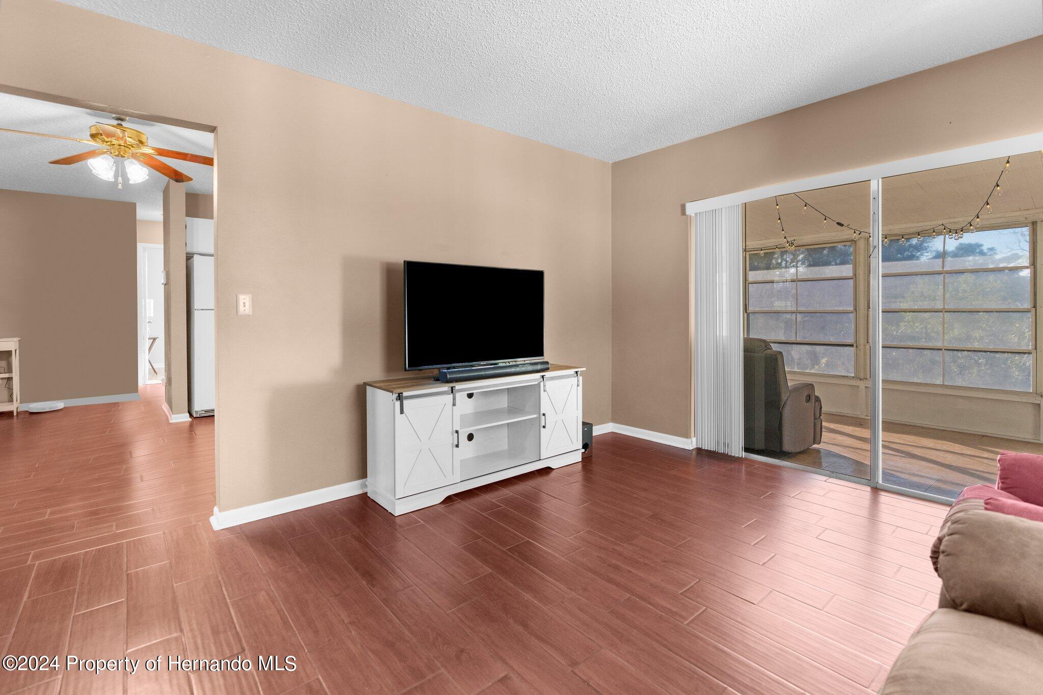 9124 Eldridge Road Spring Hill, FL 34608 - Photo 12 of 26 a view of a livingroom with wooden floor and a flat screen tv
