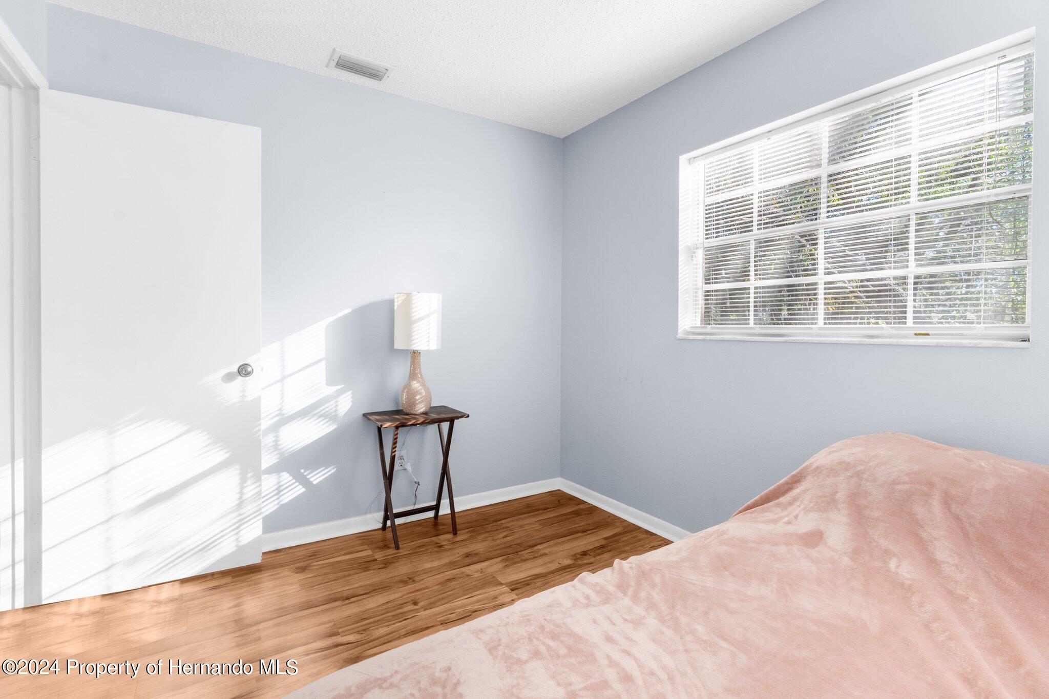 9124 Eldridge Road Spring Hill, FL 34608 - Photo 15 of 26 a view of a bedroom with wooden floor and windows