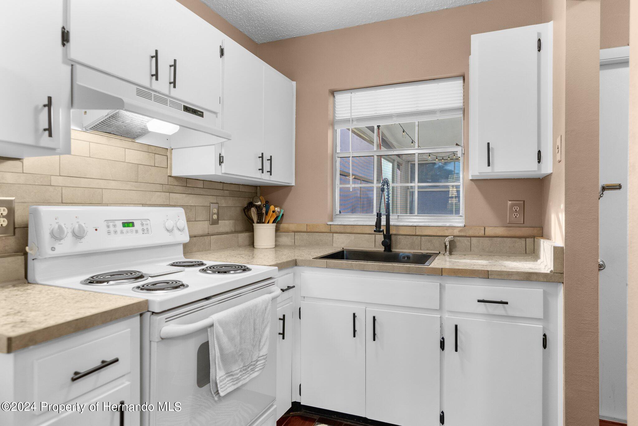 9124 Eldridge Road Spring Hill, FL 34608 - Photo 7 of 26 a kitchen with cabinets appliances a sink and a window