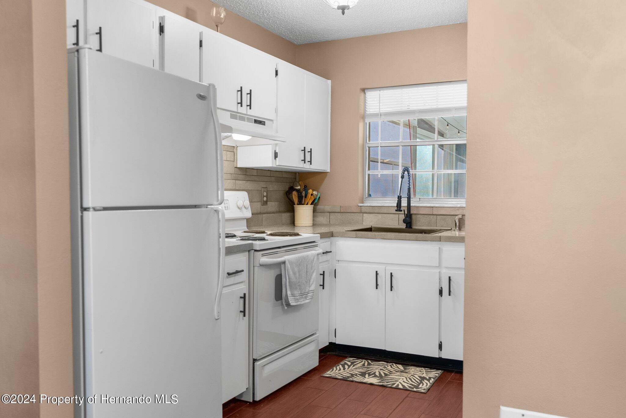 9124 Eldridge Road Spring Hill, FL 34608 - Photo 10 of 26 a kitchen with stainless steel appliances a refrigerator sink and cabinets