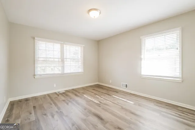 an empty room with wooden floor and windows