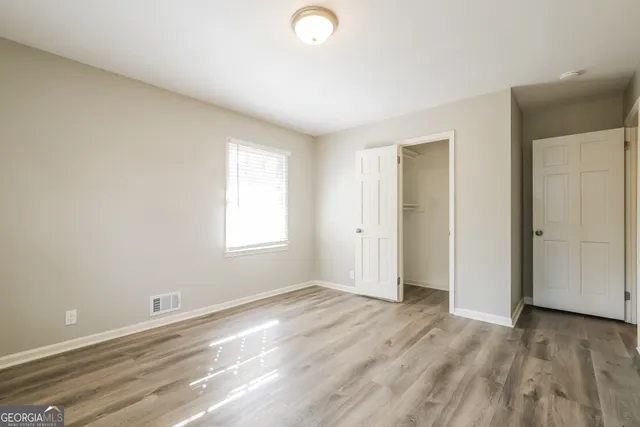 an empty room with wooden floor and windows