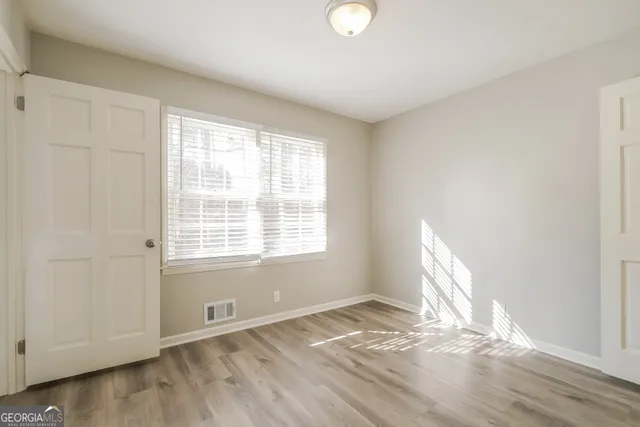an empty room with wooden floor and windows