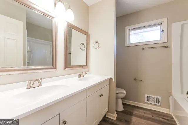 a bathroom with a double vanity sink toilet and a mirror