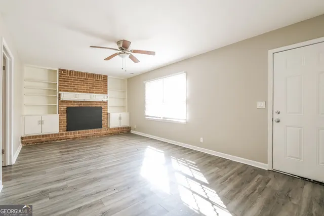 an empty room with wooden floor ceiling fan and windows