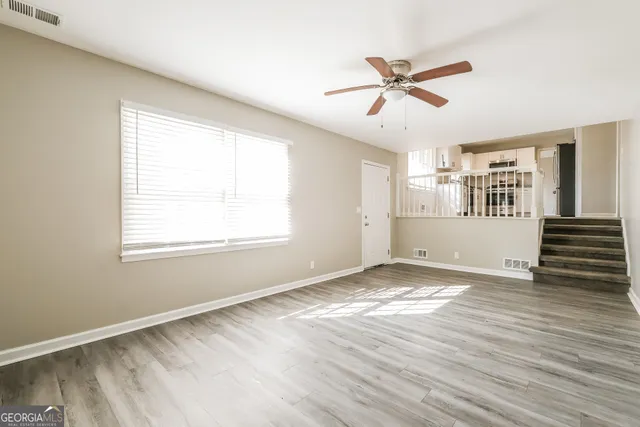 a view of an empty room with a window and wooden floor