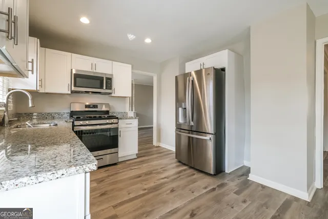 a kitchen with granite countertop a refrigerator and a stove top oven