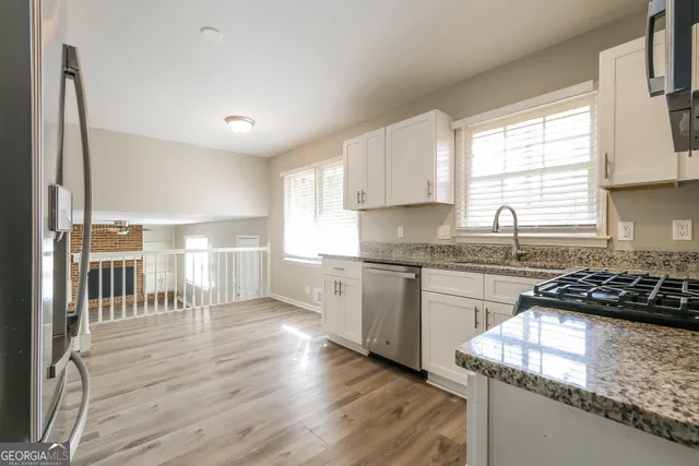 a kitchen with granite countertop a stove a sink and a refrigerator