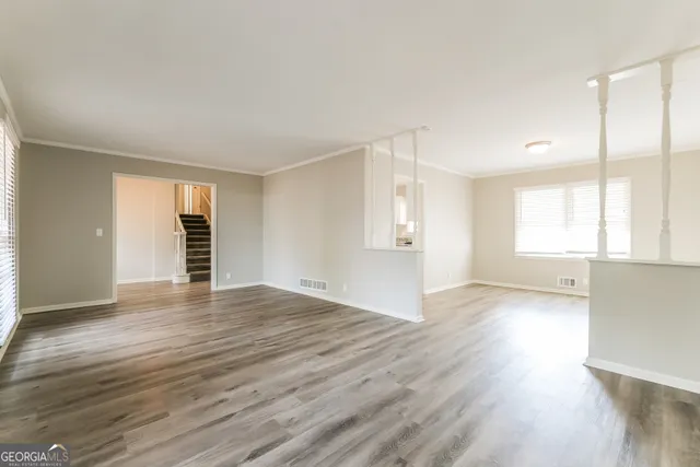 an empty room with wooden floor and windows