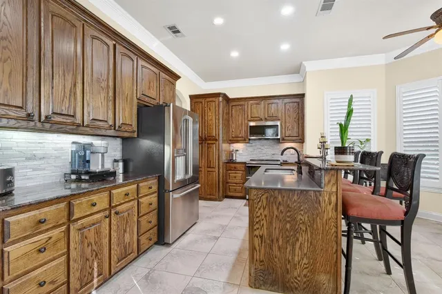 a kitchen with stainless steel appliances granite countertop a refrigerator a stove a sink a dining table and chairs with wooden floor