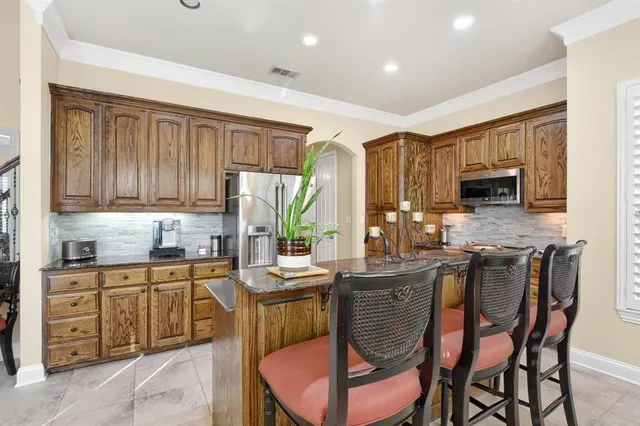 a kitchen with stainless steel appliances kitchen island granite countertop a sink a stove a dining table and chairs