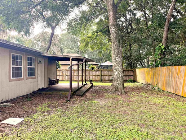 a view of a backyard with large trees and wooden fence