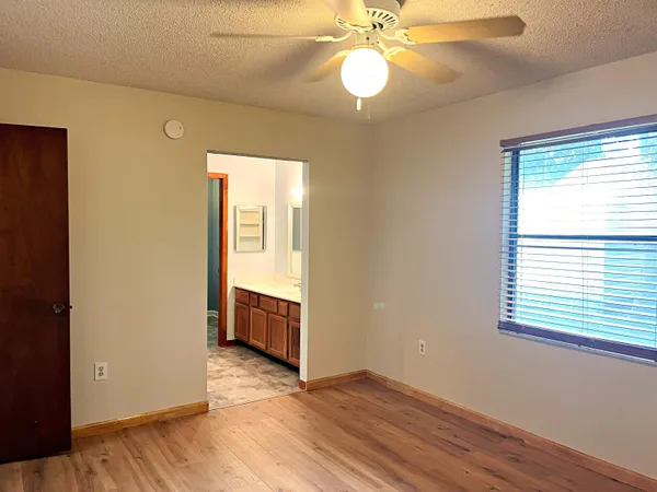 a view of an empty room with wooden floor and window