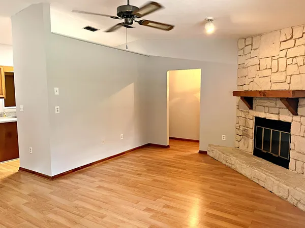 an empty room with wooden floor fireplace and windows