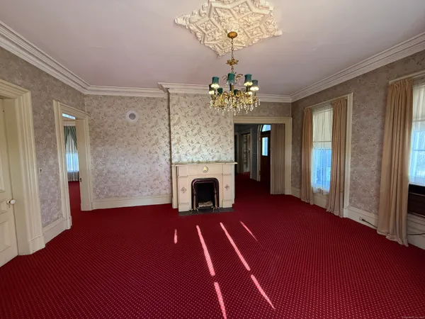 a view of a livingroom with a fireplace a chandelier and wooden floor