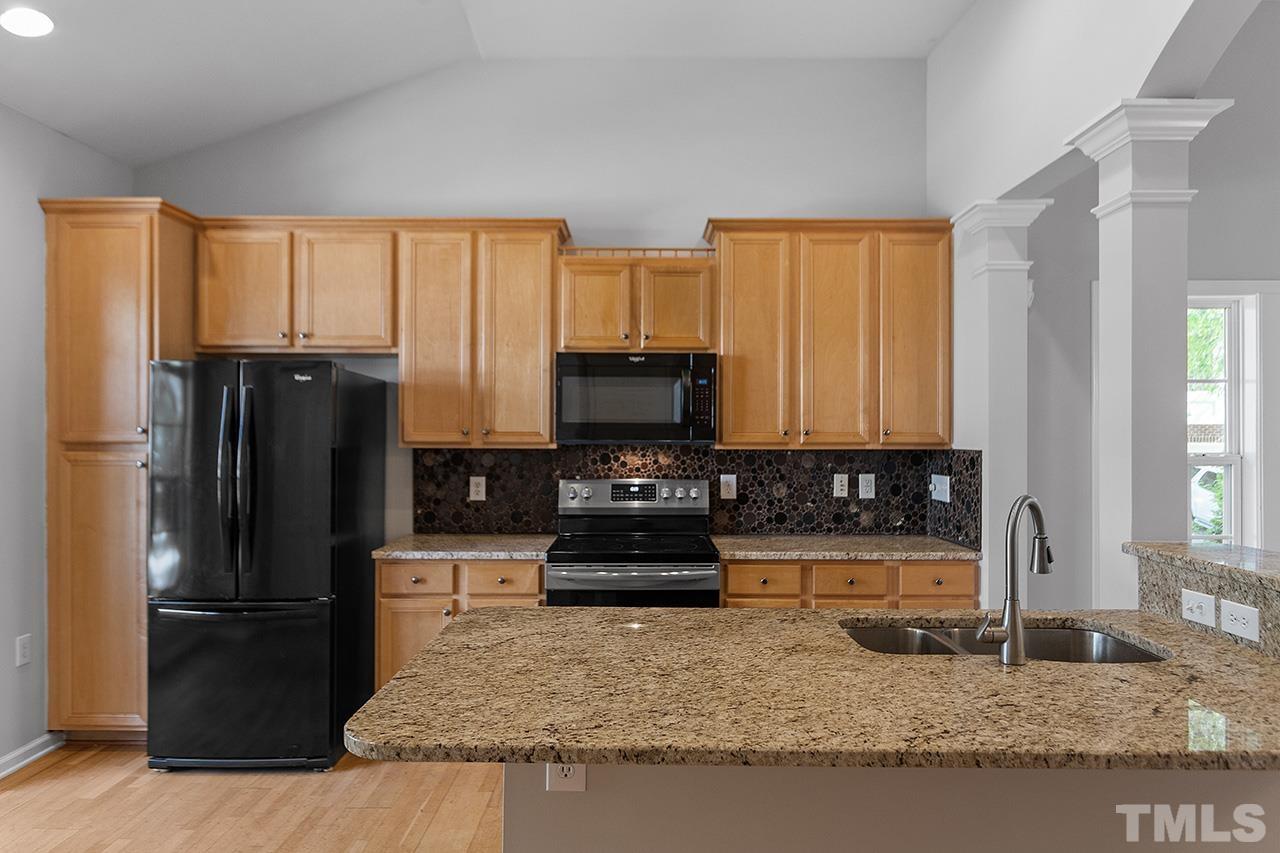 1401 Basinger Court Raleigh, NC 27612 - Photo 24 of 32 a kitchen with granite countertop a refrigerator and a sink